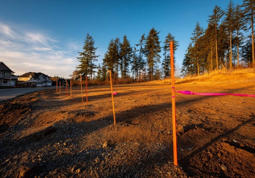 Survey stakes and a cleared Nanaimo lot prepared for a future custom home